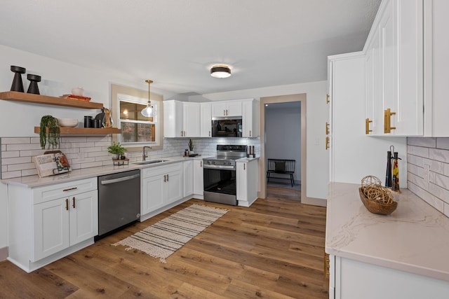 kitchen with appliances with stainless steel finishes, dark hardwood / wood-style floors, decorative light fixtures, white cabinetry, and sink