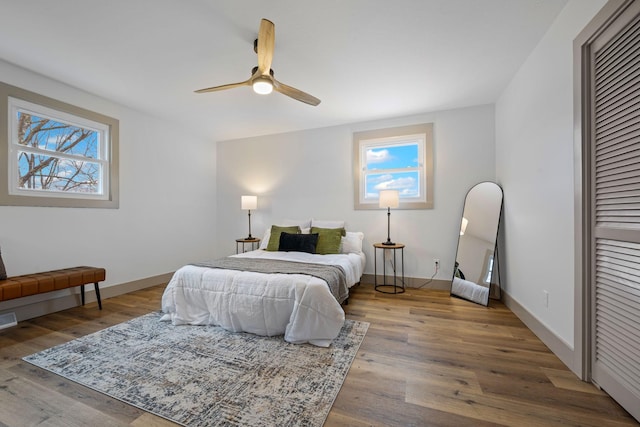 bedroom featuring hardwood / wood-style flooring, ceiling fan, and multiple windows