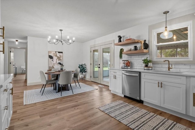 kitchen featuring decorative light fixtures, dishwasher, sink, and white cabinets