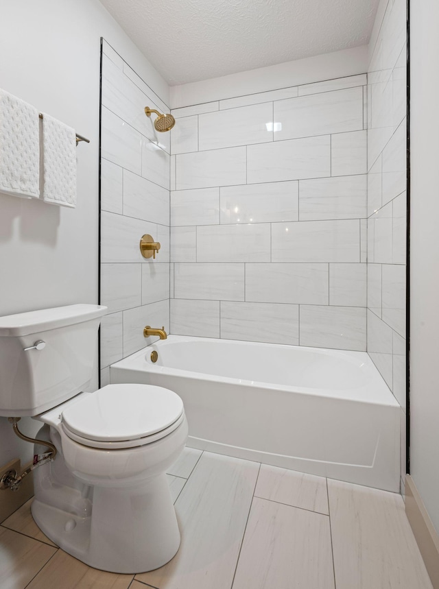 bathroom featuring toilet, tiled shower / bath combo, and a textured ceiling