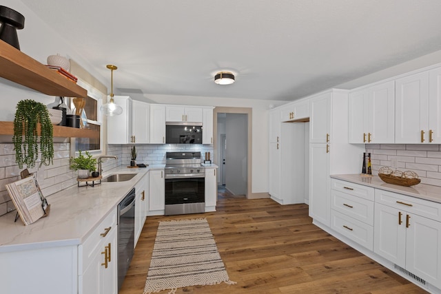 kitchen featuring sink, white cabinetry, hanging light fixtures, light wood-type flooring, and appliances with stainless steel finishes