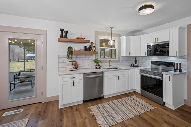 kitchen with appliances with stainless steel finishes, decorative light fixtures, sink, and white cabinets