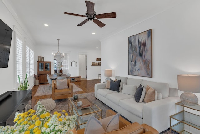 living room with crown molding, ceiling fan with notable chandelier, and hardwood / wood-style floors