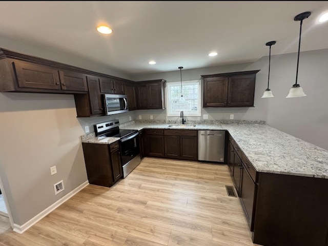 kitchen with sink, light hardwood / wood-style flooring, appliances with stainless steel finishes, hanging light fixtures, and kitchen peninsula