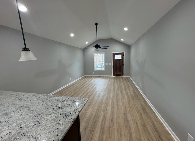 interior space featuring light stone counters, decorative light fixtures, vaulted ceiling, ceiling fan, and light hardwood / wood-style floors