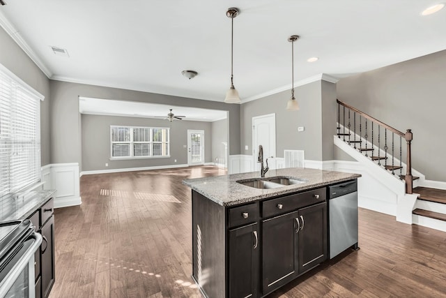 kitchen with sink, decorative light fixtures, appliances with stainless steel finishes, an island with sink, and light stone countertops