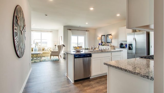 kitchen with dark wood-type flooring, sink, white cabinetry, appliances with stainless steel finishes, and a kitchen island with sink