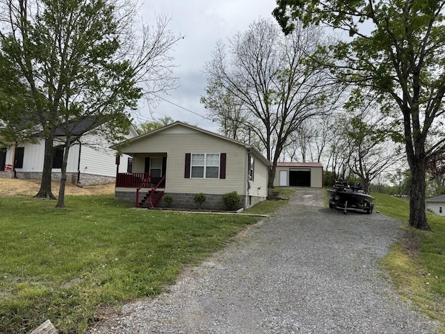 view of front of house with a detached garage, a front lawn, driveway, and an outbuilding