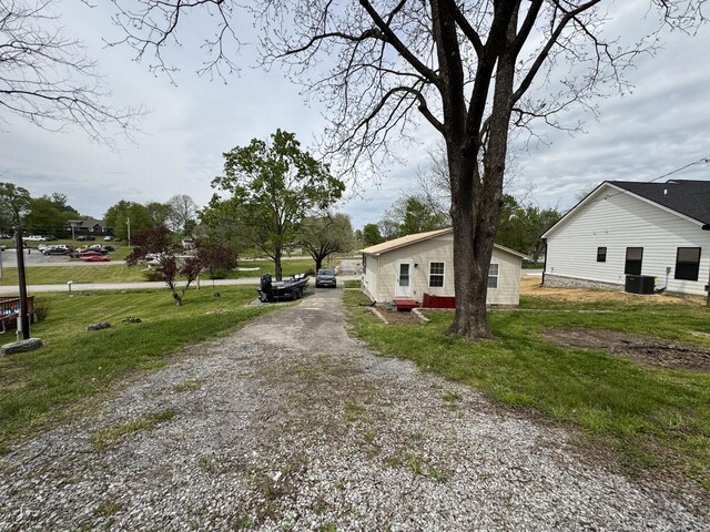 view of front of property featuring central AC, gravel driveway, and a front lawn