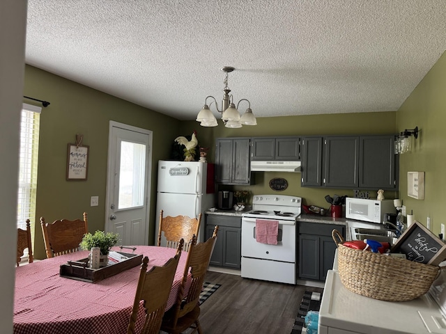 kitchen with under cabinet range hood, an inviting chandelier, white appliances, a textured ceiling, and dark wood-style flooring