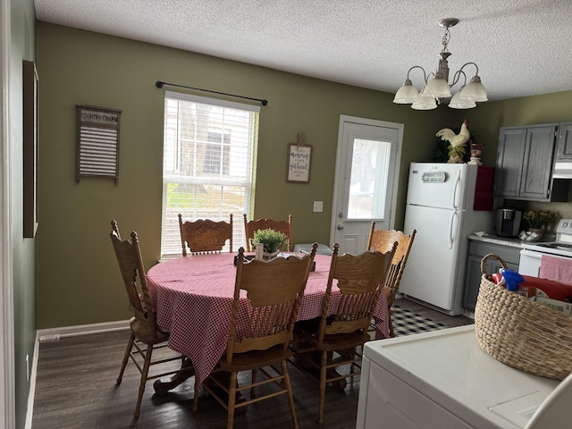 dining room featuring wood finished floors, an inviting chandelier, a textured ceiling, and washer / dryer