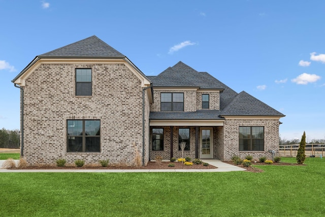 back of house featuring a yard, fence, brick siding, and a shingled roof