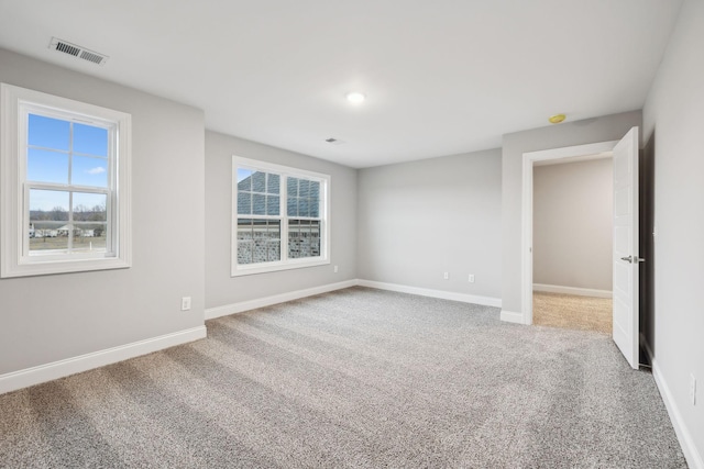 empty room featuring visible vents, baseboards, and carpet