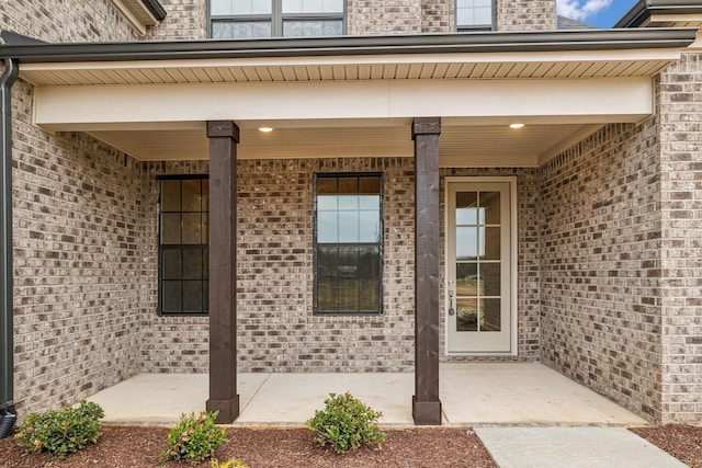 entrance to property featuring a patio and brick siding