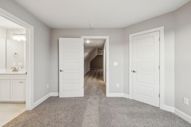 unfurnished bedroom with light colored carpet, sink, and ensuite bath