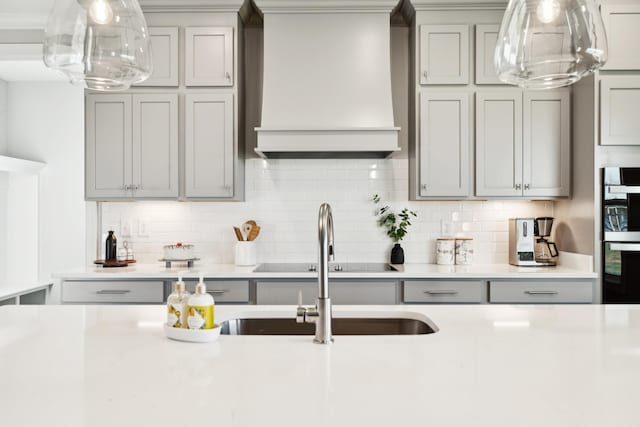 kitchen with custom exhaust hood, black appliances, gray cabinets, and light countertops