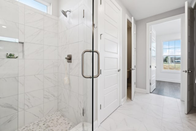 full bathroom featuring marble finish floor, a stall shower, and baseboards