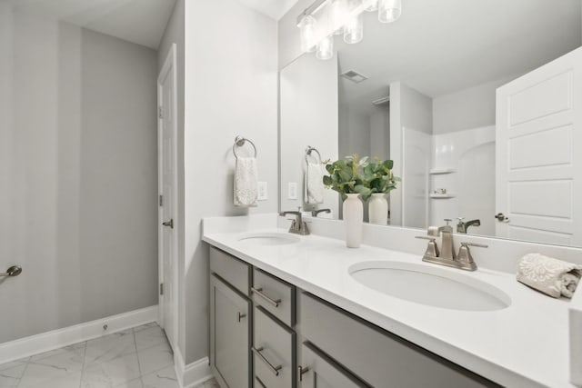 bathroom featuring a sink, visible vents, baseboards, and marble finish floor