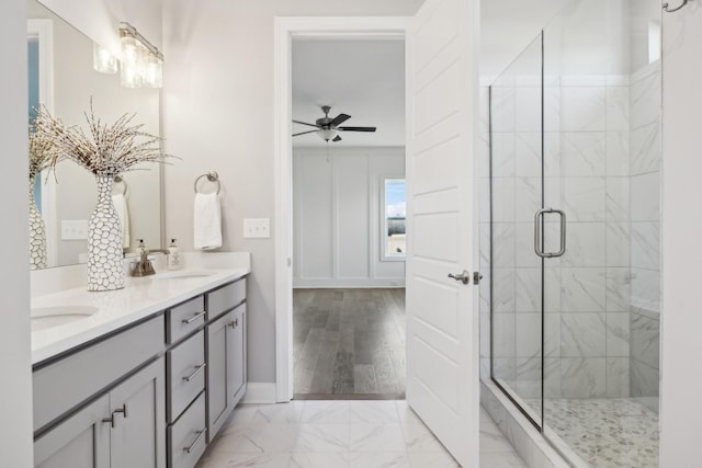 bathroom with ceiling fan, double vanity, a stall shower, marble finish floor, and a sink