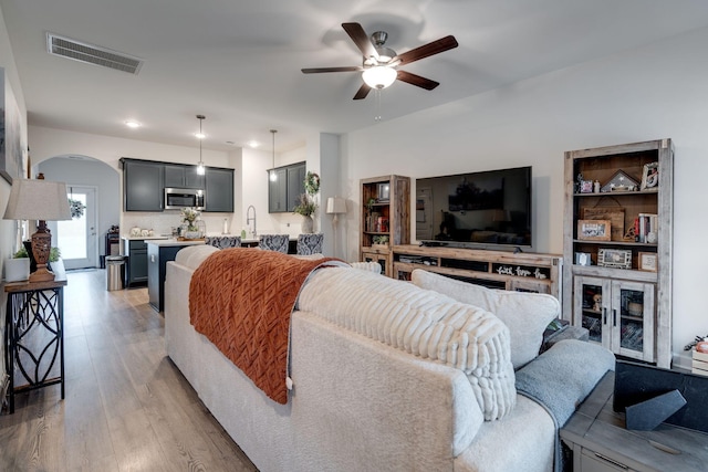 living room with ceiling fan, sink, and light hardwood / wood-style floors