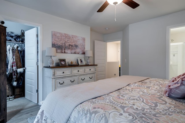 bedroom featuring light hardwood / wood-style flooring, ceiling fan, ensuite bathroom, a walk in closet, and a closet