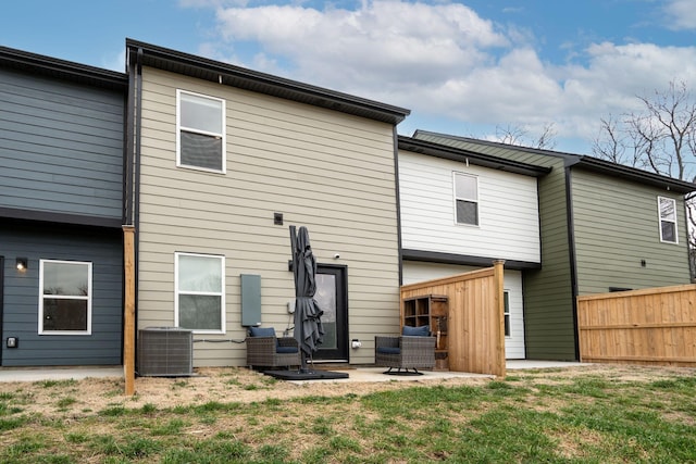 rear view of house with cooling unit, a patio area, and a lawn