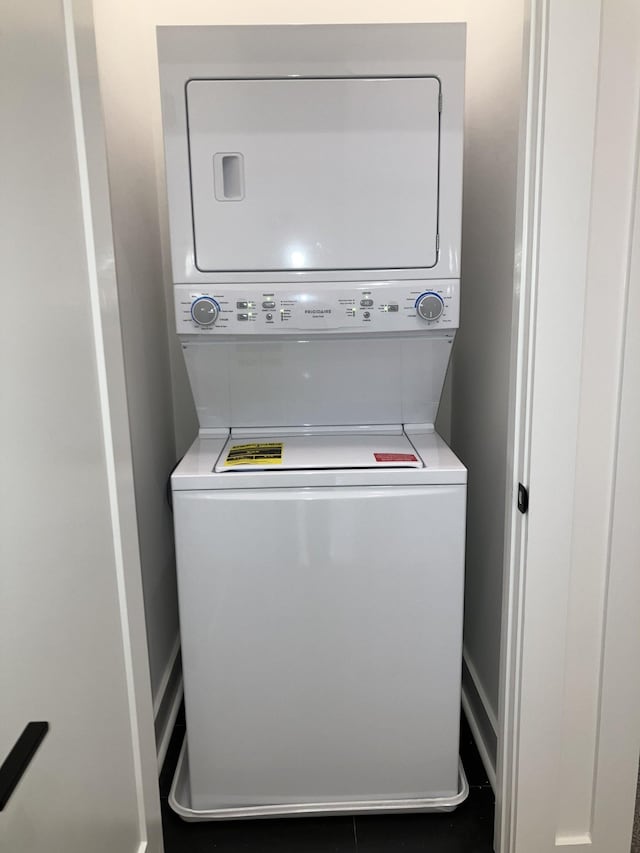 clothes washing area with stacked washing maching and dryer