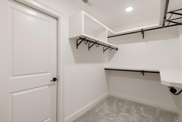 walk in closet with light carpet