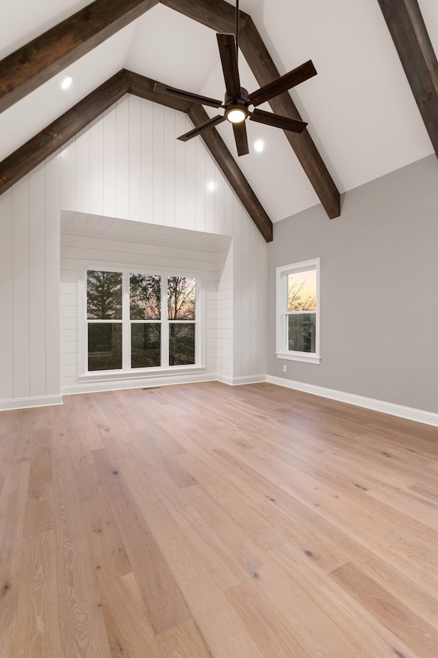 unfurnished living room with beamed ceiling, ceiling fan, high vaulted ceiling, and light hardwood / wood-style floors