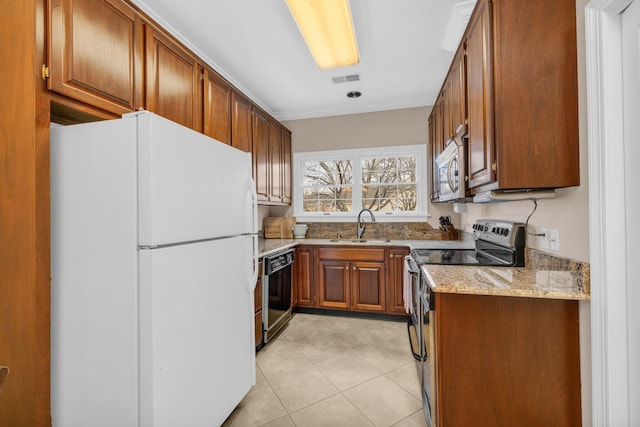 kitchen with a sink, light stone countertops, brown cabinets, and stainless steel appliances