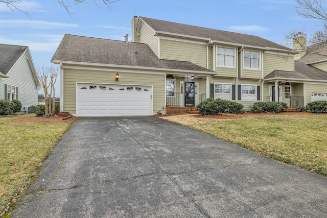 traditional-style house featuring a shingled roof, a front yard, covered porch, aphalt driveway, and a garage