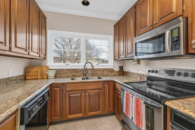 kitchen with a sink, ornamental molding, light stone counters, brown cabinets, and stainless steel appliances