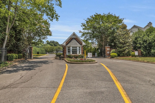 view of road featuring a gated entry, a gate, and curbs