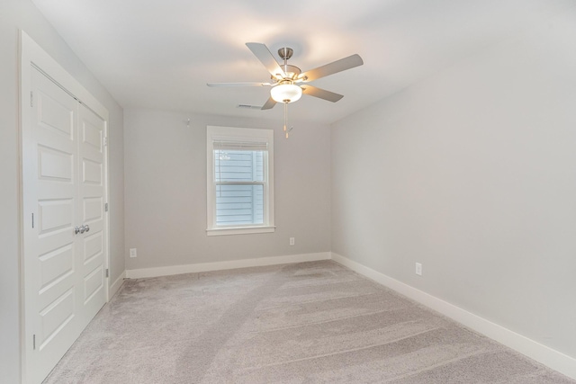 empty room with ceiling fan and light colored carpet