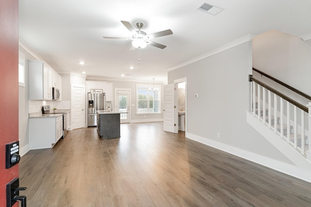 kitchen featuring appliances with stainless steel finishes, dark hardwood / wood-style floors, white cabinets, ornamental molding, and a center island with sink