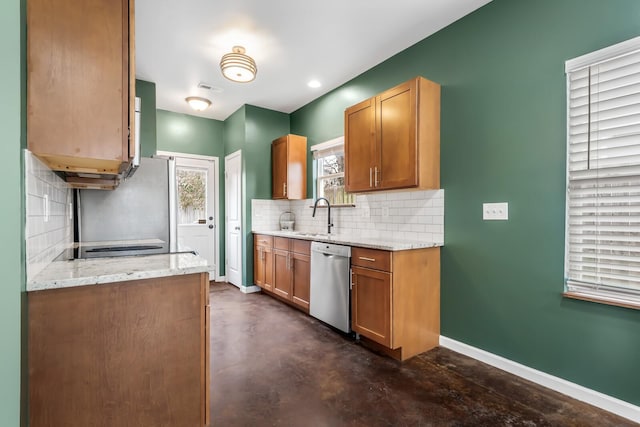 kitchen with light stone counters, stainless steel appliances, sink, and decorative backsplash