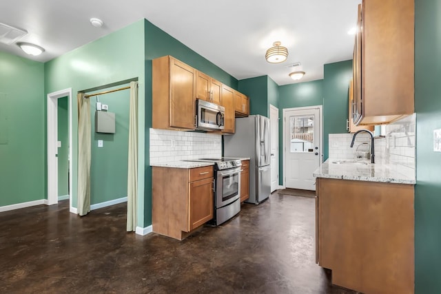 kitchen featuring stainless steel appliances, light stone countertops, sink, and backsplash