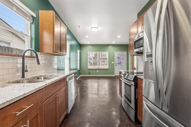 kitchen with light stone counters, appliances with stainless steel finishes, sink, and backsplash