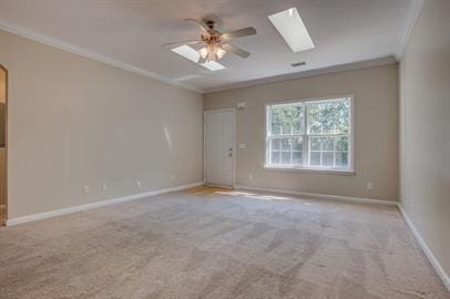 spare room featuring ornamental molding, light colored carpet, ceiling fan, and a skylight