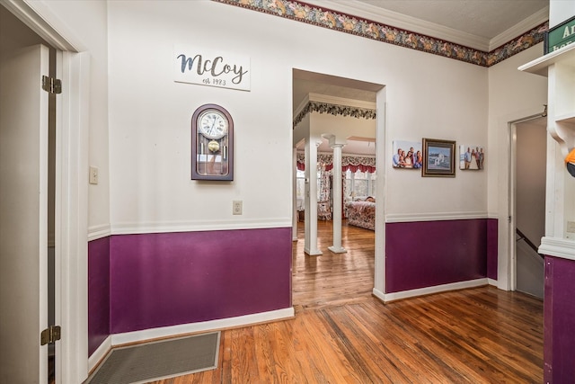 hall with crown molding, wood-type flooring, and decorative columns