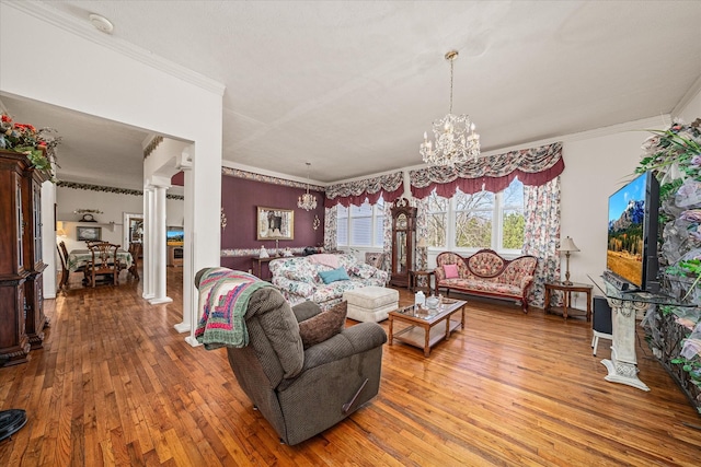 living room with an inviting chandelier, ornamental molding, hardwood / wood-style floors, and ornate columns