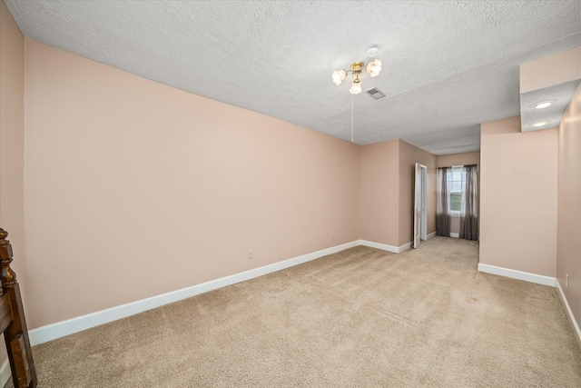 empty room with light carpet and a textured ceiling