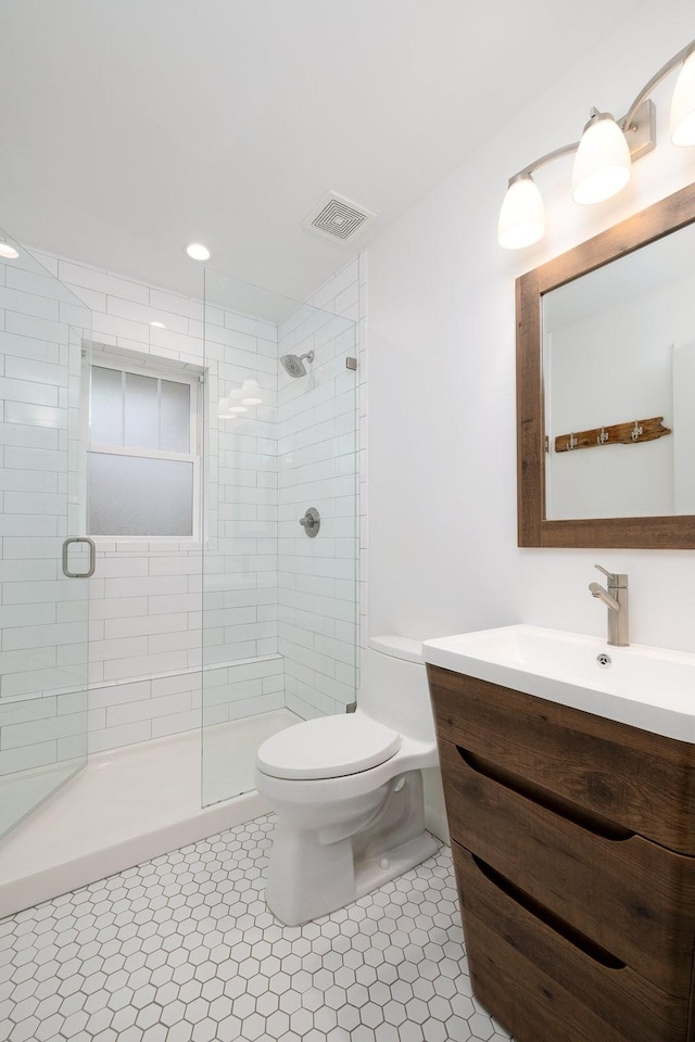 bathroom featuring vanity, a shower with shower door, tile patterned floors, and toilet