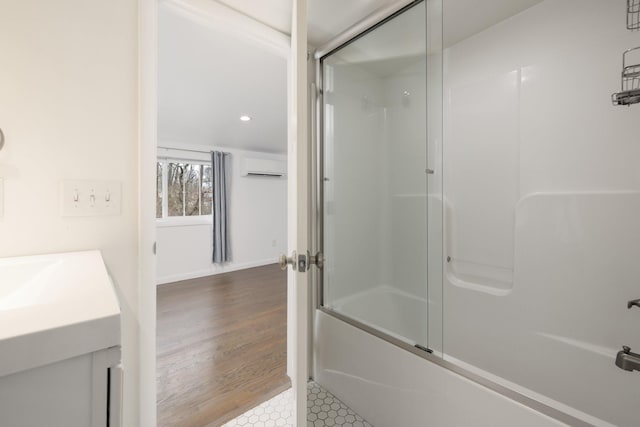 bathroom featuring hardwood / wood-style flooring, bath / shower combo with glass door, an AC wall unit, and vanity