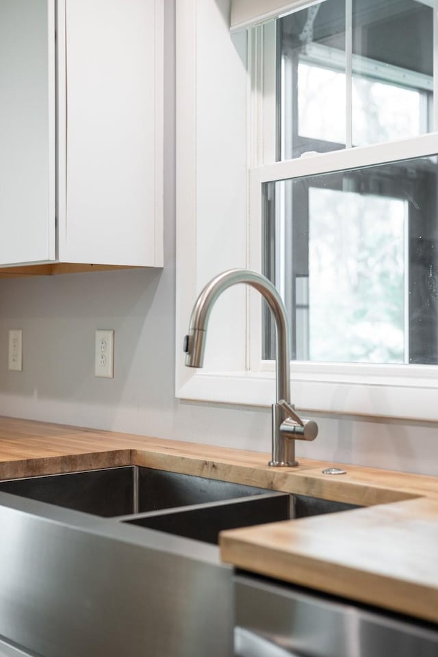 details with white cabinetry, stainless steel dishwasher, and sink