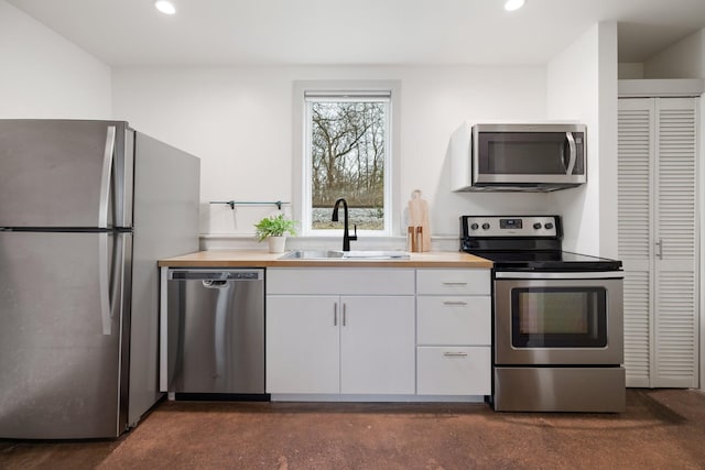 kitchen with sink, stainless steel appliances, wooden counters, and white cabinets