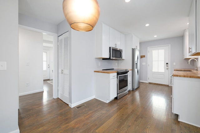 kitchen featuring white cabinetry, wood counters, stainless steel appliances, and sink