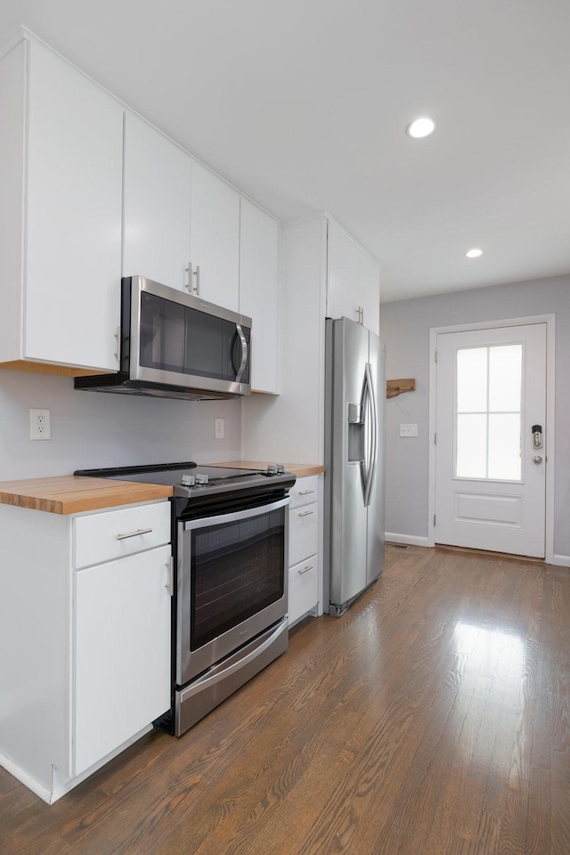 kitchen featuring appliances with stainless steel finishes, dark hardwood / wood-style floors, white cabinets, and butcher block countertops