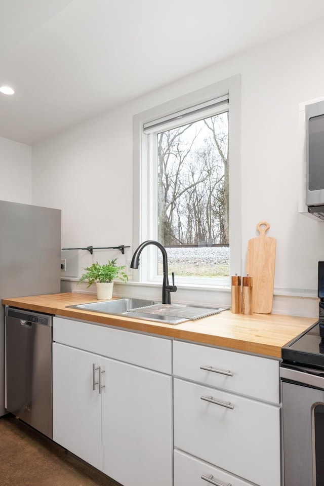 kitchen featuring white cabinetry, sink, wooden counters, and appliances with stainless steel finishes