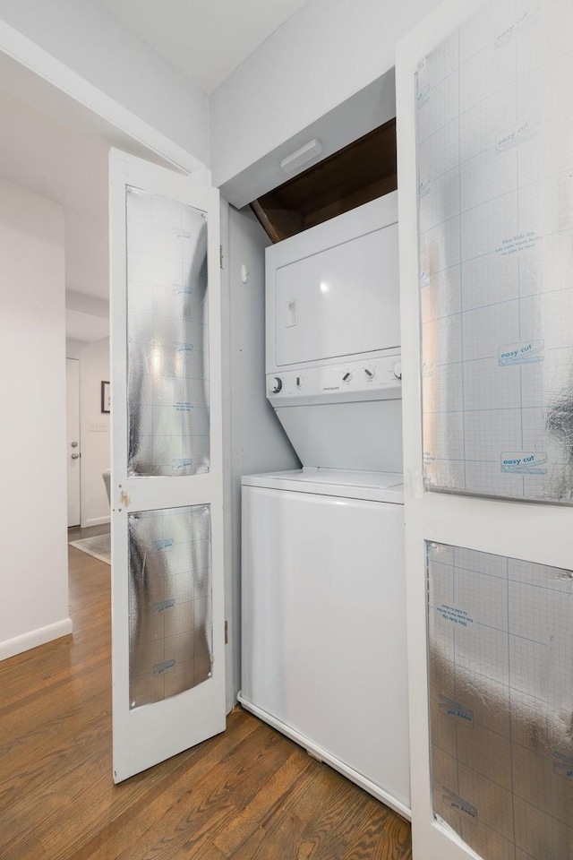 clothes washing area with stacked washer / dryer and dark hardwood / wood-style flooring